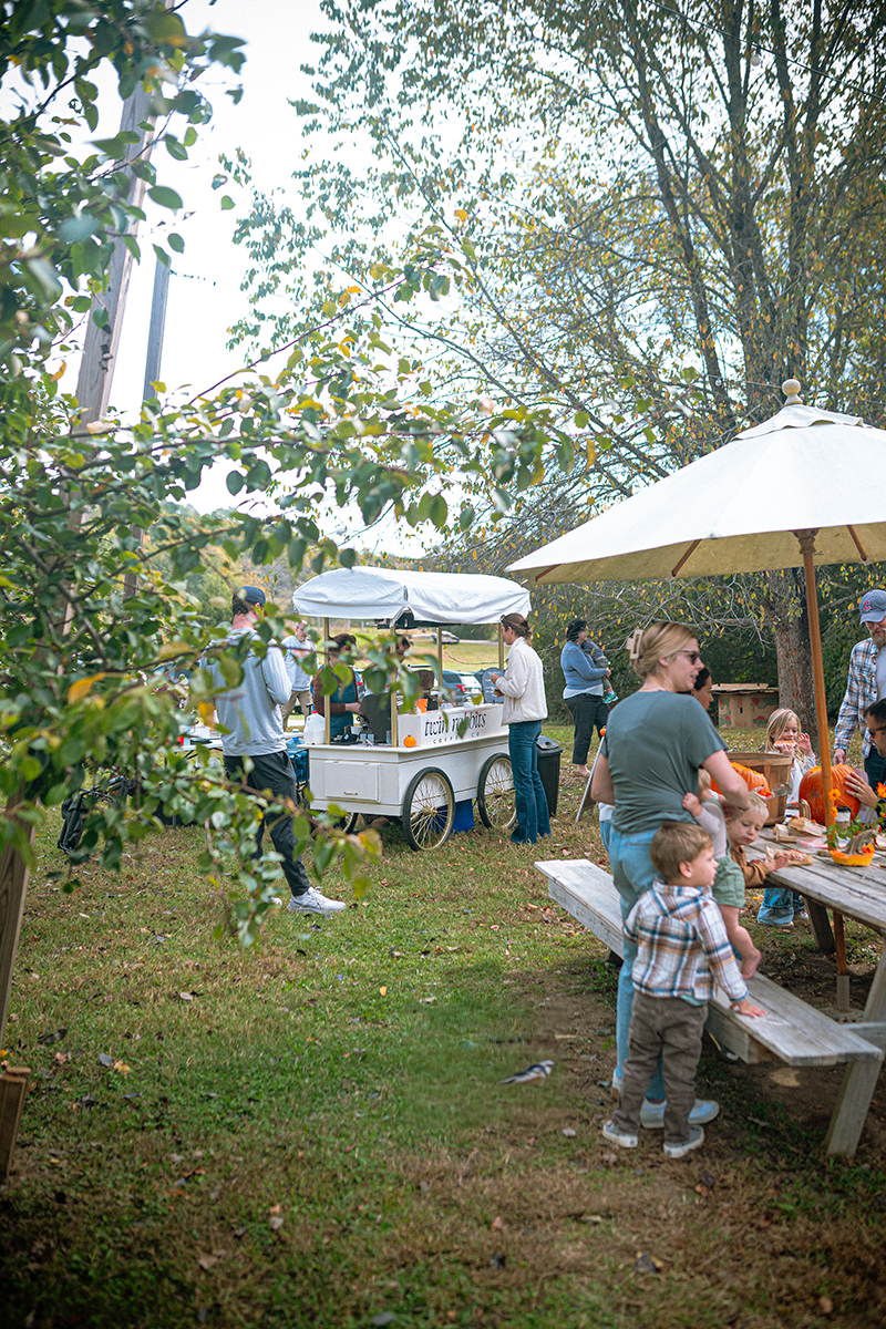 Twin Rabbits Coffee cart set up at Bloomsbury Farm in Smyrna, Tennessee, surrounded by pumpkins, with families and kids carving pumpkins at picnic tables on a crisp fall afternoon.